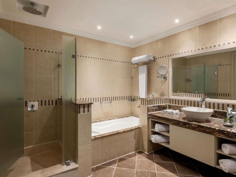 Une salle de bains avec douche vitrée, baignoire et vasque posée