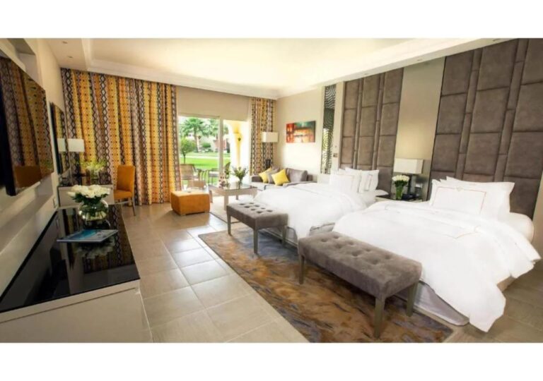 Une chambre à deux lits avec un coin salon, ouverte sur le jardin