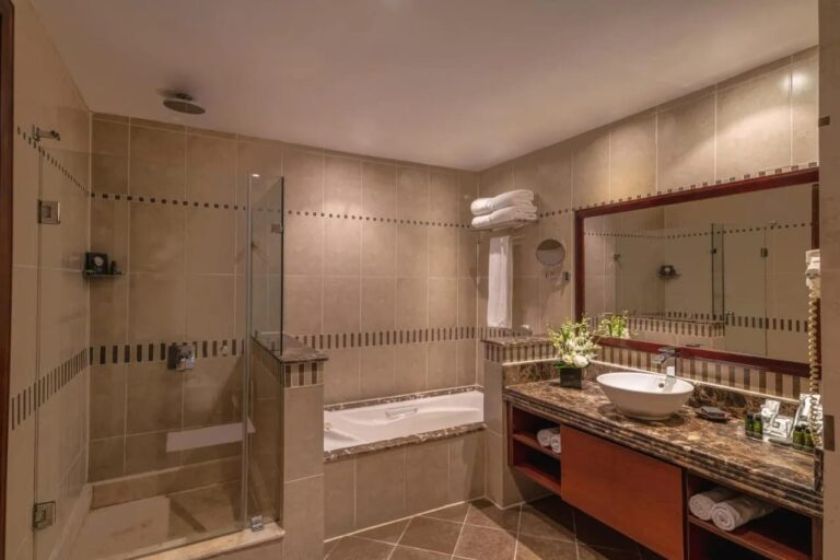 Une salle de bains avec douche vitrée, baignoire et grand miroir