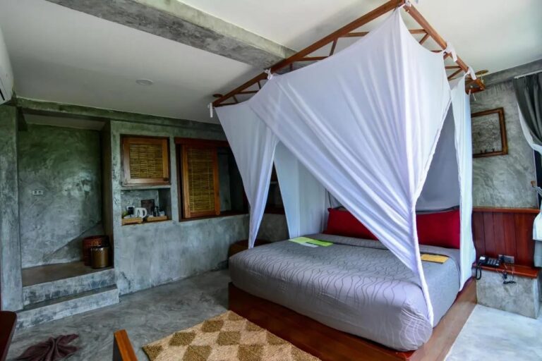 Une chambre au lit sous moustiquaire, avec un coin thé dans une niche du mur
