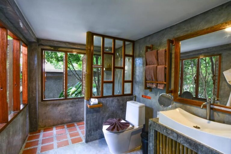Une salle de bains avec une douche derrière une cloison vitrée encadrée de bois