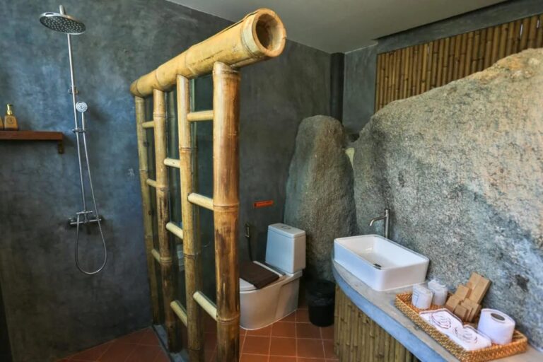 Une salle de bains construite contre un gros rocher, avec une douche et une vasque