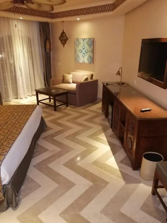 Le coin salon d'une chambre, avec un canapé, un bureau en bois et un sol à chevrons