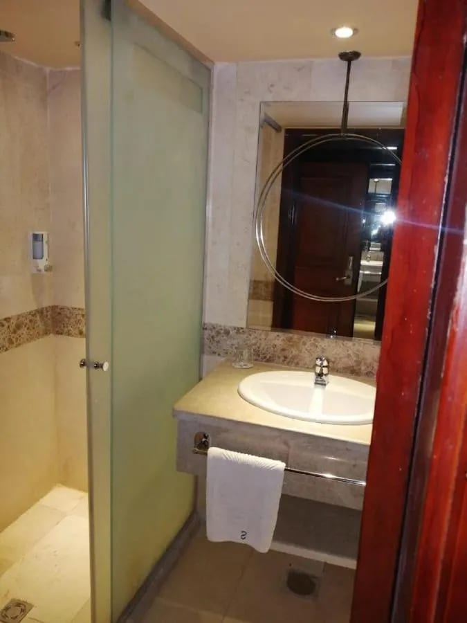 Une douche vitrée et un lavabo sous un miroir rond