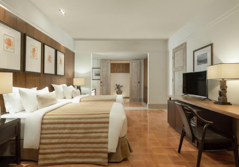 Une chambre au grand lit avec un bureau et des gravures au mur