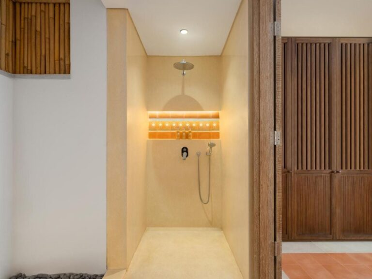 Une douche à l'italienne derrière une porte en bois