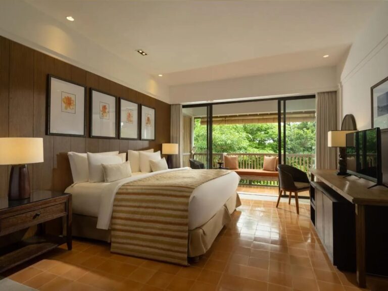 Une chambre au grand lit ouverte sur une terrasse et le jardin
