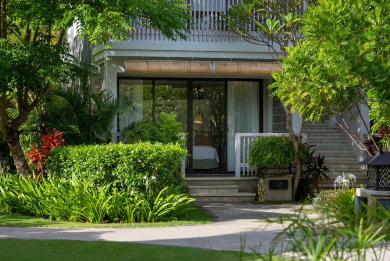 L'entrée d'un bâtiment des chambres, entourée de plantes tropicales