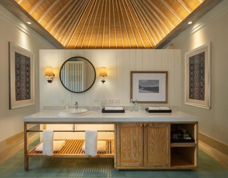 Une salle de bains avec vasque, miroir rond et meuble en bois