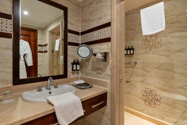 Une salle de bains claire avec vasque, miroir à cadre sombre et douche vitrée