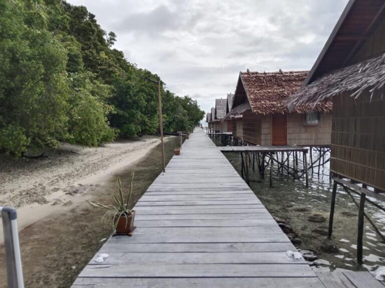 Une passerelle en bois entre la plage et les bungalows sur pilotis