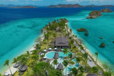 Vue aérienne du Two Seasons Coron, ses piscines et ses palmiers sur une étroite bande de terre entre deux plages