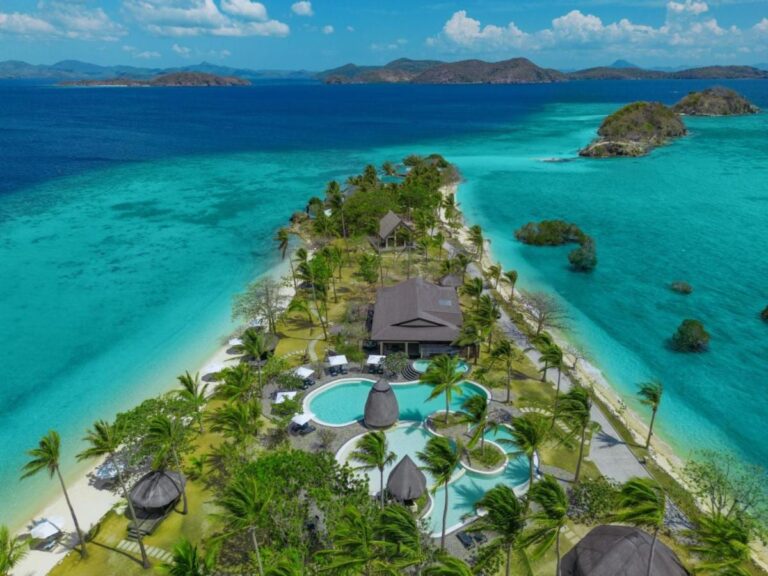 Vue aérienne du Two Seasons Coron, ses piscines et ses palmiers sur une étroite bande de terre entre deux plages